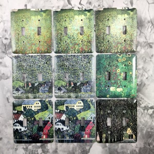 May include: Nine light switch covers with different artistic designs. Each cover features a double toggle switch and a unique painting style. The designs include a green and yellow floral pattern, a green and blue landscape, and a black and white forest scene.