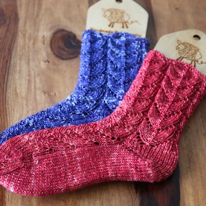 May include: Two pairs of knitted socks with a lacy pattern. One pair is red with white flecks and the other is blue with white flecks.