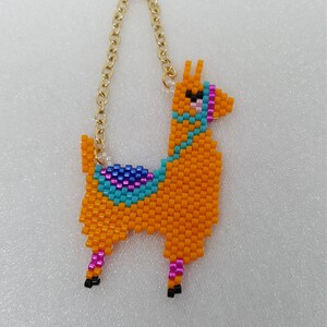 May include: A beaded llama keychain with a gold chain. The llama is orange with blue, pink, and purple accents.