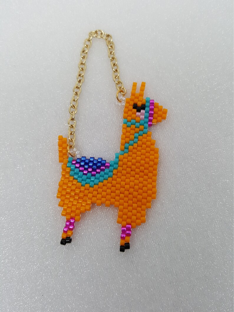 May include: A beaded llama keychain with a gold chain. The llama is orange with blue, pink, and purple accents.