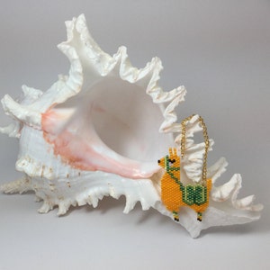 May include: A beaded llama charm with a gold chain hanging from a white seashell.
