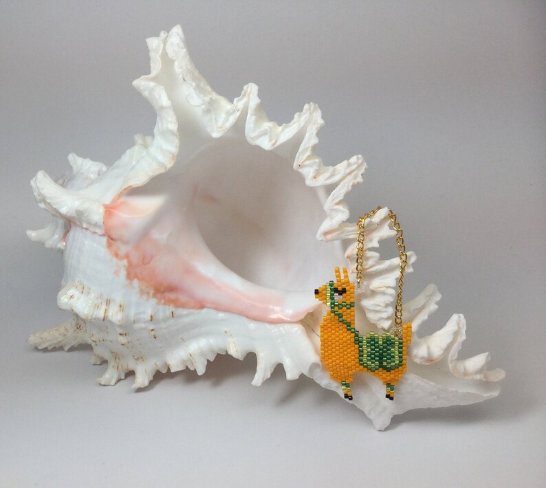 May include: A beaded llama charm with a gold chain hanging from a white seashell.