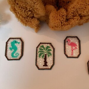 May include: Five small, rectangular, beaded, framed designs with various tropical themes. The designs include a pineapple, a seahorse, a palm tree, a flamingo, and a flower.