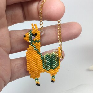 May include: A beaded llama charm with a gold chain. The llama is orange with green and black details.