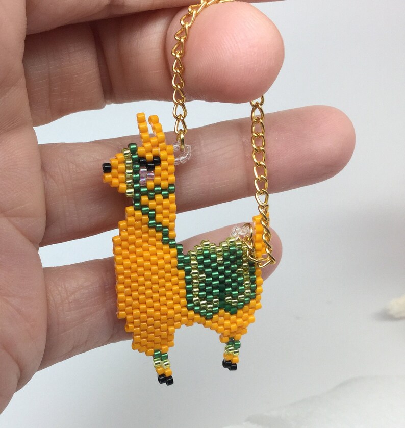 May include: A beaded llama charm with a gold chain. The llama is orange with green and black details.