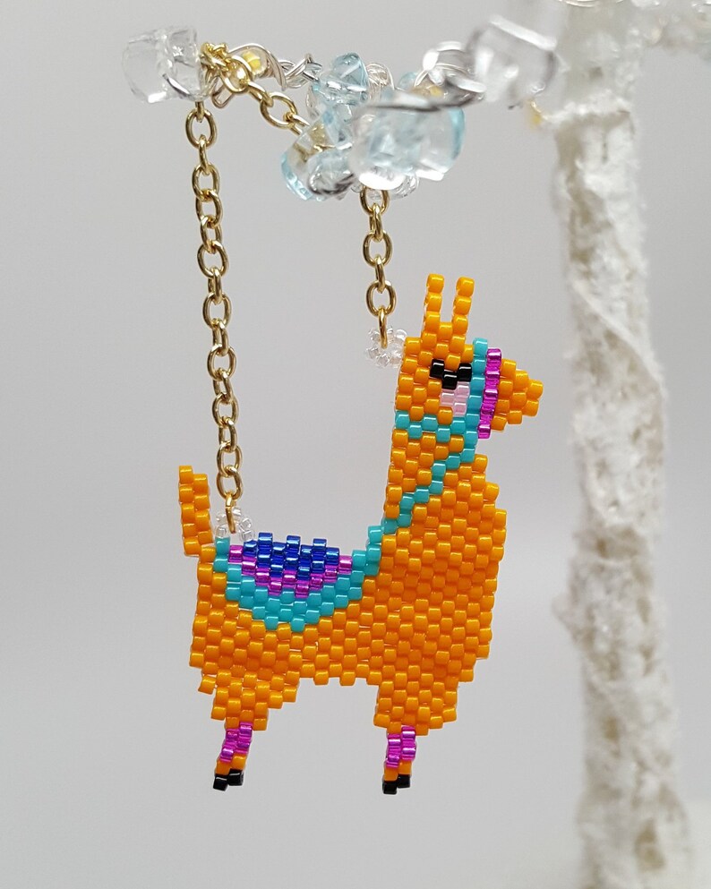 May include: A beaded llama charm with a gold chain. The llama is orange with blue, pink, and purple accents.