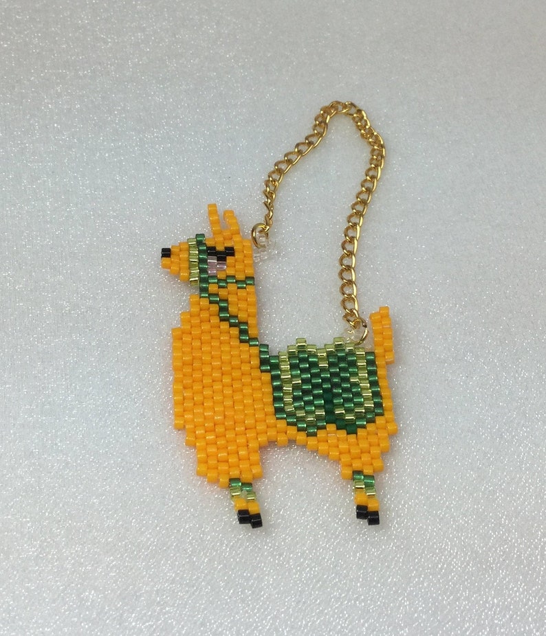 May include: A beaded llama keychain with a gold chain. The llama is orange with green and gold accents.