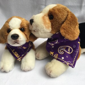 May include: Two plush beagle dog toys wearing purple bandanas with gold LSU lettering and paisley designs.