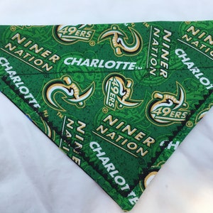 May include: Green and black dog bandana featuring the text "Niner Nation Charlotte" and a repeated logo of a green and gold "49ers" logo.