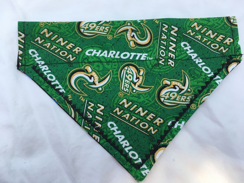 May include: Green and black dog bandana featuring the text "Niner Nation Charlotte" and a repeated logo of a green and gold "49ers" logo.