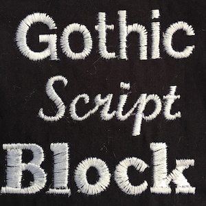 May include: Close-up of white embroidered text on black fabric. The text reads "Gothic Script Block".