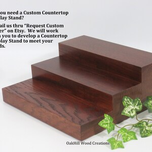 May include: Three-tiered wooden display stand made of dark red stained wood. The stand is made of solid wood and has a natural wood grain. The stand is perfect for displaying small items, such as jewelry, candles, or figurines.  Do you need a Custom Countertop Display Stand? E-mail us thru "Request Custom Order" on Etsy. We will work with you to develop a Countertop Display Stand to meet your needs. OakHill Wood Creations