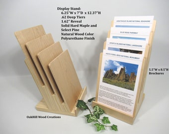 May include: A wooden brochure holder with four tiers for displaying brochures. The holder is made of solid hard maple and select pine with a natural wood color and polyurethane finish. The holder measures 6.25 inches wide by 7 inches deep by 12.37 inches high. The brochures measure 5.5 inches wide by 8.5 inches high.