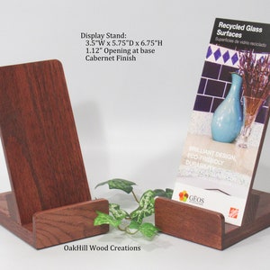 May include: Two wooden display stands with a 1.12 inch opening at the base. The stands are 3.5 inches wide, 5.75 inches deep, and 6.75 inches high. The stands are made of oak and have a Cabernet finish. The stands are holding a brochure that says "Recycled Glass Surfaces".