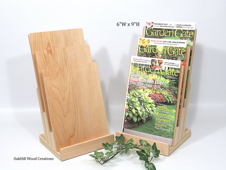 May include: A wooden magazine rack with four slots to hold magazines. The rack is made of natural wood and is 15.2 cm wide by 22.9 cm high. The rack is holding three copies of "Garden Gate" magazine.