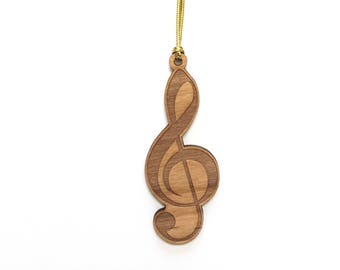 Pode incluir: Um ornamento de madeira em forma de clave de sol, com um cordão dourado preso.