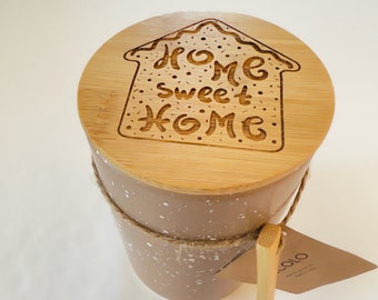 Tarro de cerámica con diseño de pan de jengibre, grabado con láser con la frase "Hogar, dulce hogar" en la tapa de madera.