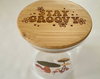Tarro de cristal decorado con hongos y grabado a láser con la frase Stay Groovy en la tapa de madera.