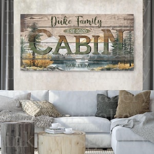 May include: Wooden cabin sign with the text "Duke Family" and "Cabin" in large letters. The sign includes the text "EST 2020" and "Hawley, PA". The background features a lake and trees.