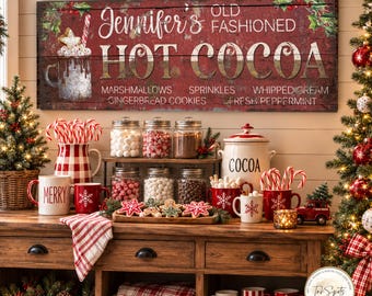 May include: A rectangular wooden sign with a distressed red finish features the text Jennifer's Old Fashioned Hot Cocoa, along with a graphic of a mug and a list of toppings. The sign is displayed above a counter filled with holiday decor.