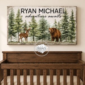 May include: A rectangular wall art print featuring a watercolour forest scene with a brown bear and a deer. The text RYAN MICHAEL and adventure awaits is printed in black at the top. The artwork has a weathered, vintage-style border finish.