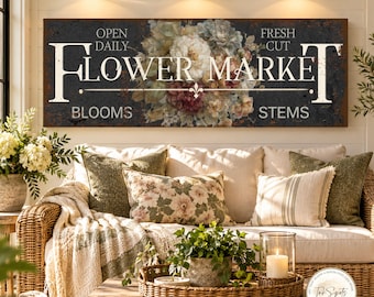 May include: A rectangular wall sign with a dark, weathered background featuring a central floral arrangement of white, pink, and green flowers. The text reads "OPEN DAILY FRESH CUT FLOWER MARKET BLOOMS STEMS" in white, serif lettering.