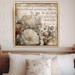 May include: A framed floral print with a bouquet of white and brown flowers and green leaves. The print includes text: "Let the morning bring me word of your unfailing love..." and "Psalm 143:8". The frame is light brown.