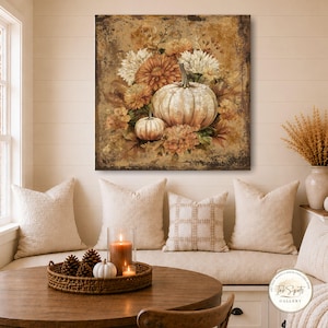 May include: A square wall art print featuring a large, light-colored pumpkin and a smaller pumpkin nestled among autumn flowers and foliage in shades of brown, orange, and cream, set against a distressed, textured, dark-toned background.