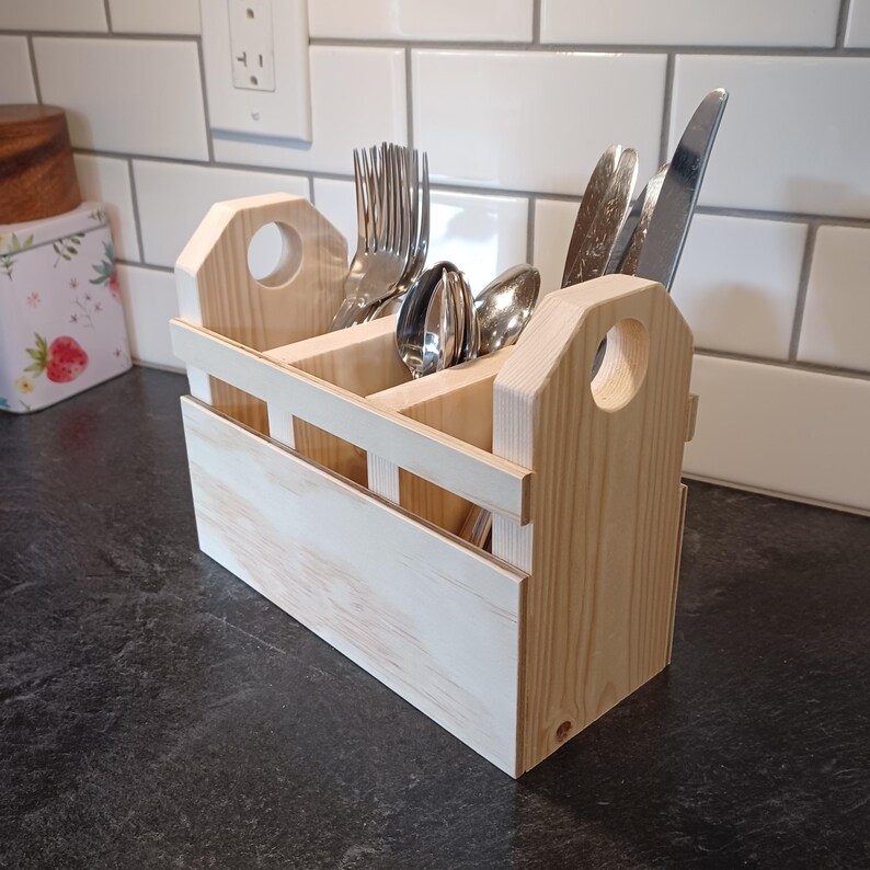 K&ouml;nnte beinhalten: Ein Besteckorganizer aus Holz mit drei F&auml;chern f&uuml;r Gabeln, L&ouml;ffel und Messer. Der Organizer ist aus Naturholz gefertigt und hat einen rustikalen Look.
