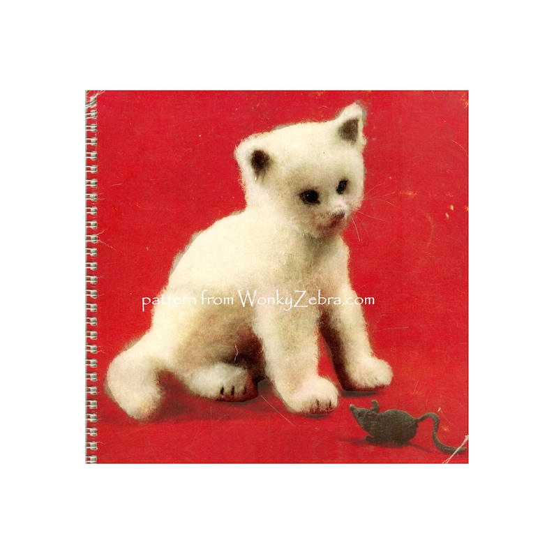 May include: A white knitted kitten sitting on a red background, looking at a gray knitted mouse. The text "pattern from WonkyZebra.com" is printed below the kitten.