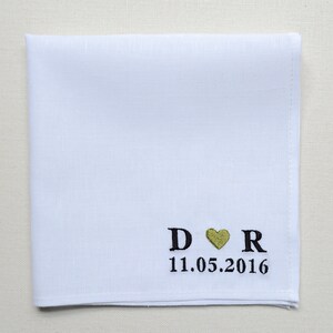 May include: White linen pocket square with black embroidery of the letters "D" and "R" with a gold heart in between. The date "11.05.2016" is embroidered below the letters.