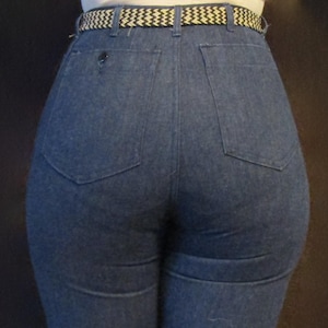 May include: A pair of dark blue denim jeans with a high waist and a wide leg. The jeans have a belt loop and a belt with a black and white pattern.