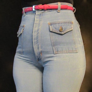 May include: A pair of light blue high-waisted jeans with a pink belt and a large patch pocket on the right side.