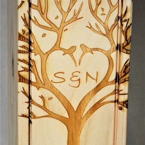 May include: A wooden box with a laser-engraved design of a tree with a heart in the branches. The text "S & N" is inside the heart. The box is inscribed with "Scott & Nancy October 7, 2007 Happy 10th Anniversary".