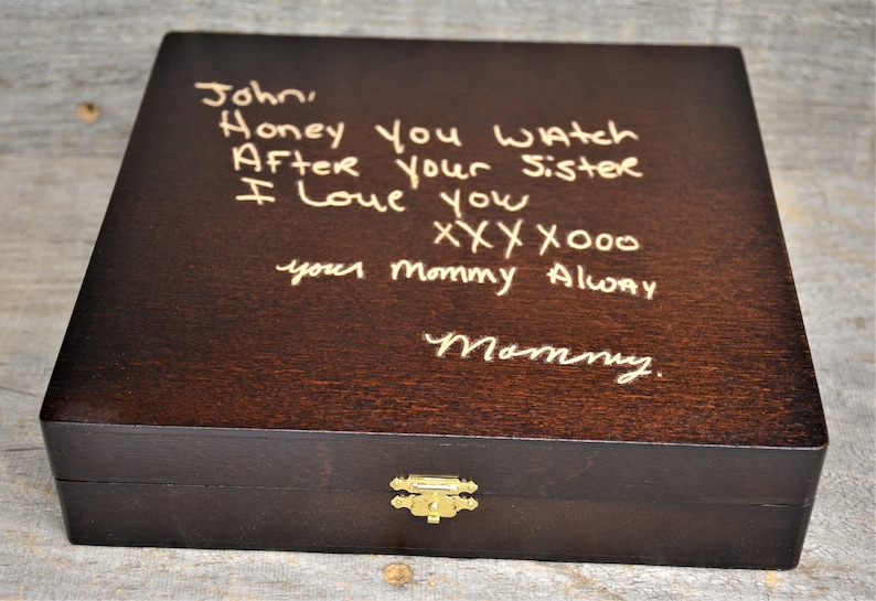 Pode incluir: Uma caixa de madeira castanho escura com uma trava dourada. A parte superior da caixa tem uma mensagem escrita &agrave; m&atilde;o em tinta dourada que diz "John, Honey you watch After your sister I love you xxx x000 your mommy Alway Mommy."