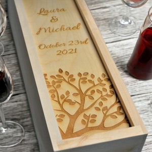 May include: A wooden wine box featuring a laser-engraved tree design. The box is personalised with the names "Laura & Michael" and the date "October 23rd 2021".