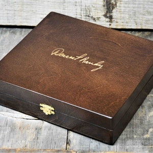 May include: A dark brown wooden box with a gold latch and the inscription "Dearest Randy" on the top.