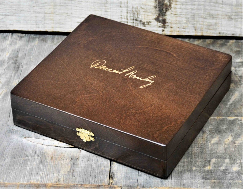 May include: A dark brown wooden box with a gold latch and the inscription "Dearest Randy" on the top.
