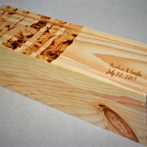May include: A wooden box with a burnt wood design on the top and the text "Nathan & Leslie July 22, 2017" engraved on the side.