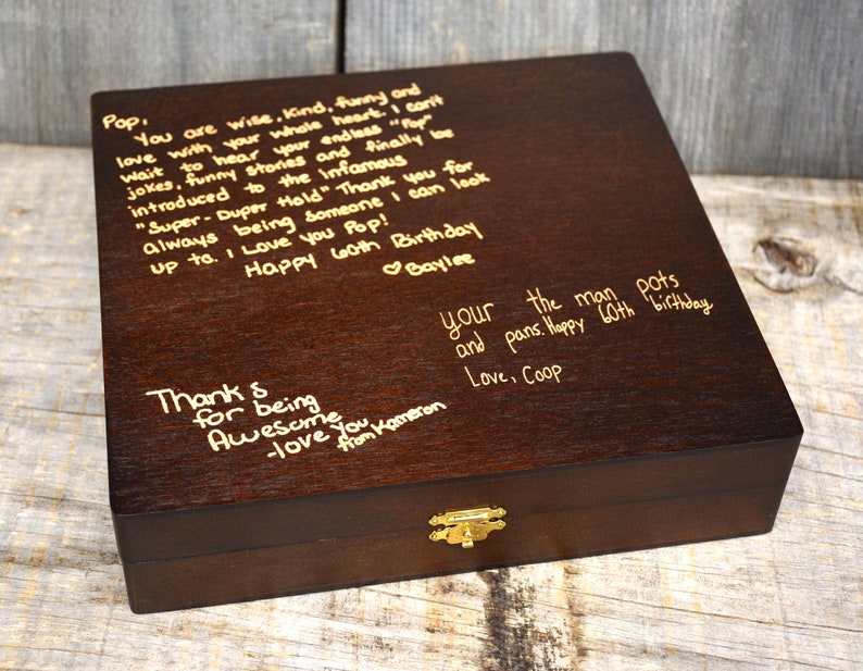 Pode incluir: Uma caixa de madeira castanho escuro com uma trava dourada. A parte superior da caixa &eacute; gravada com uma mensagem escrita &agrave; m&atilde;o que diz: "Pop, You are wise, kind, funny and love with your whole heart. I can't wait to hear your endless "Top" jokes, funny stories and finally be introduced to the infamous "Super-Duper Hold" Thank you for always being someone I can look up to. I love you Pop! Happy 60th Birthday Baylee. Thank for being Awesome you Kameron -love from your the man pots and pans. Happy 60th birthday Love, Coop"