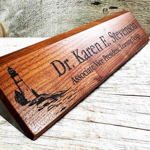 May include: A wooden desk nameplate with a lighthouse image and the text "Dr. Karen E. Stevenson Associate Vice President, Learning Design."