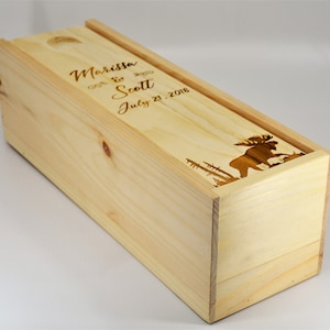 May include: A wooden wine box with a laser engraved design of a moose and trees. The box is personalised with the names "Marissa & Scott" and the date "July 21, 2018".