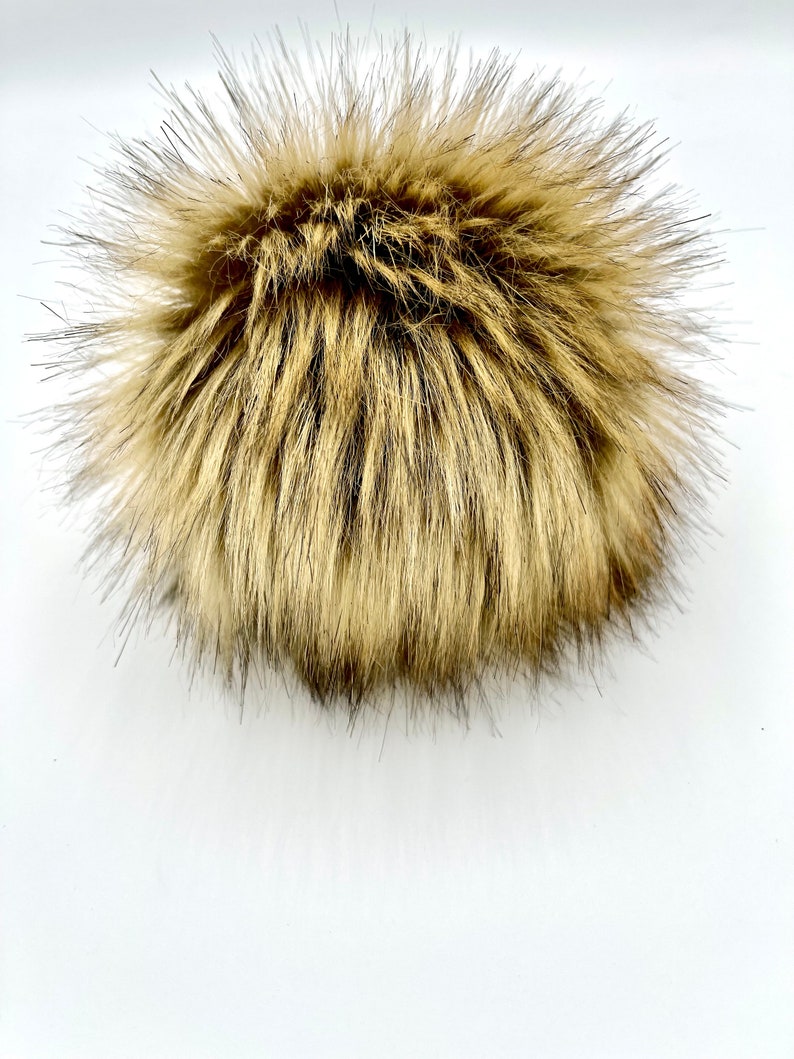 May include: A fluffy brown faux fur pom pom. The pom pom is made of soft, synthetic fur and is perfect for adding a touch of warmth and style to any hat or accessory.