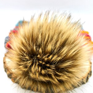 May include: A brown faux fur pom pom for a hat. The pom pom is fluffy and soft.