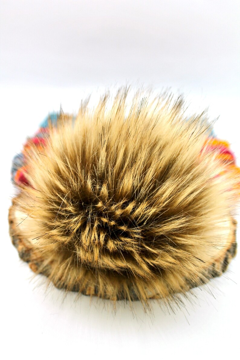 May include: A brown faux fur pom pom for a hat. The pom pom is fluffy and soft.