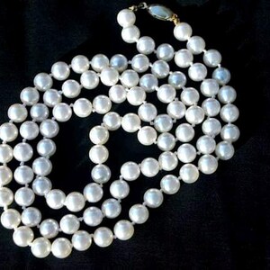 May include: A long strand of white pearls, strung together on a thin gold chain. The pearls are round and smooth, and they have a subtle iridescent sheen.