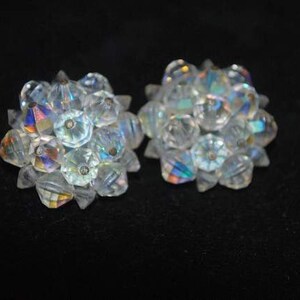 May include: A pair of iridescent clear crystal earrings. Each earring is a cluster of small, faceted crystals.