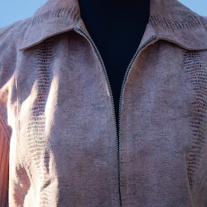 Könnte beinhalten: Eine rosa Strickjacke mit Reißverschluss und einem strukturierten Muster. Die Jacke hat ein geripptes Strickdesign an den Ärmeln und einen Kragen.