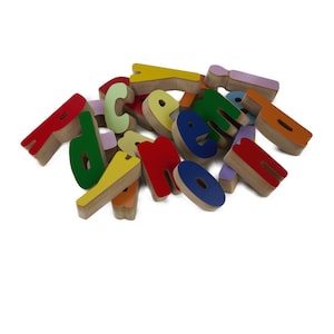 May include: A pile of colorful wooden letters, including red, green, blue, yellow, and purple. The letters are in various sizes and shapes, and some are stacked on top of each other.