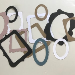 May include: Assortment of paper frames in various shapes and sizes. The frames are in black, white, brown, pink, and blue.
